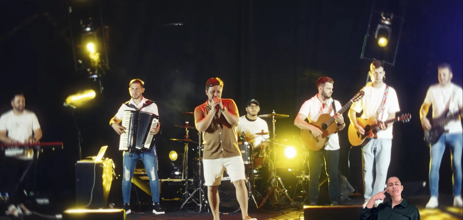 Régis Palma cantando com a banda sob luzes amarelas